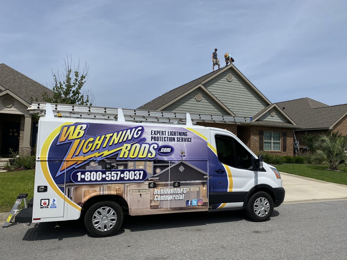 WB Lightning Rods van at a home while two crew members work on the roof